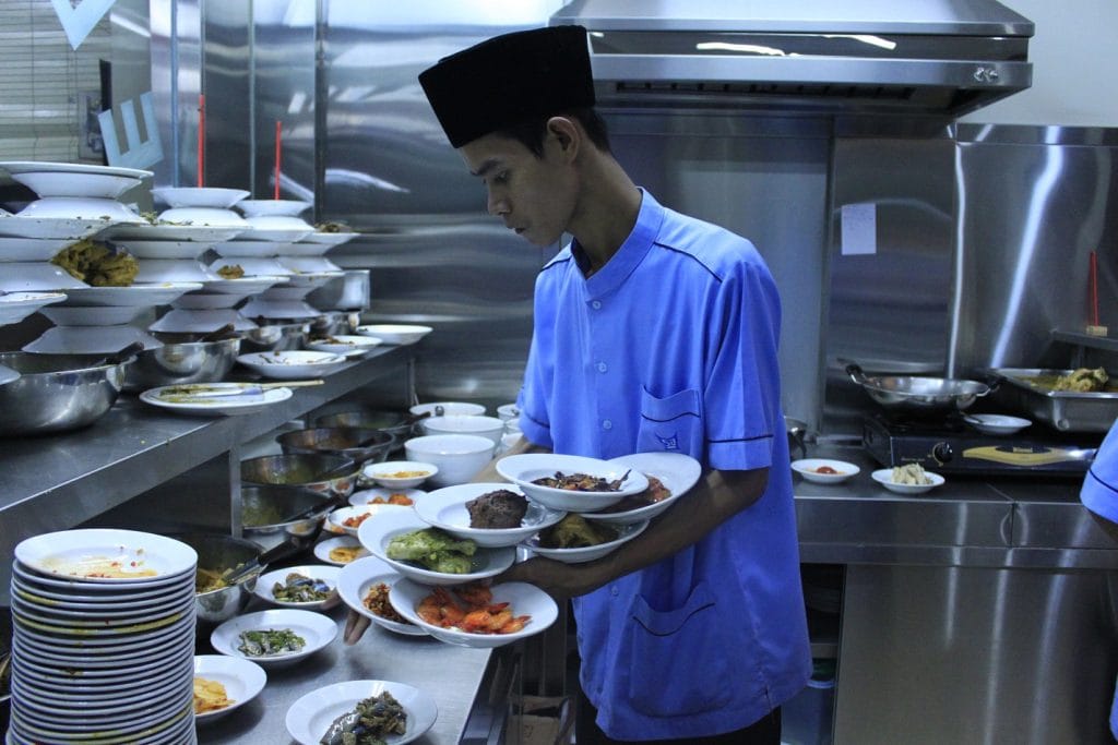 Pekerja rumah makan Padang membawakan makanan